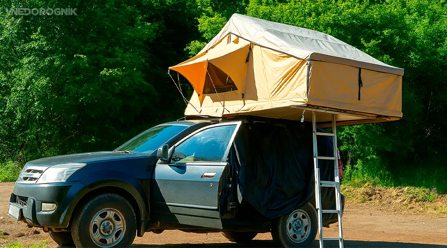 Unfolded roof tent on SUV roof against mountain scenery
