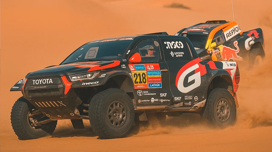Two SUVs overcoming sand dunes during a Dakar Rally stage in Saudi Arabia.