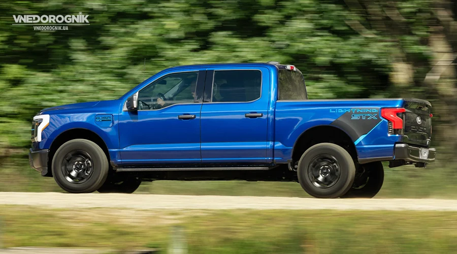 Новий електричний пікап F-150 Lightning STX, що демонструє свій дизайн на лісовій дорозі.
