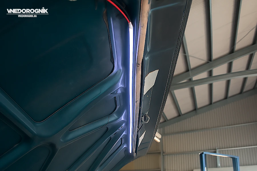 Cool white LED strip on a reinforcing rib under the hood, evenly illuminating the space.