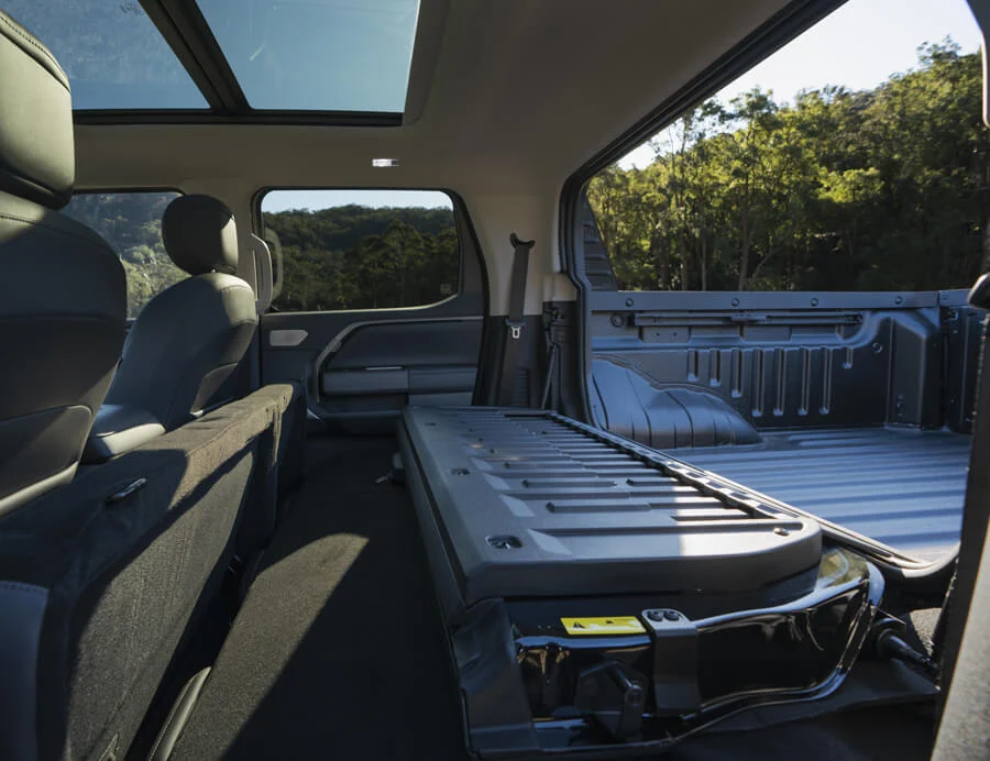 Інтер'єр пікапа MG U9 зі складеними задніми сидіннями та відкритою перегородкою Smart Hatch для перевезення довгомірних вантажів.